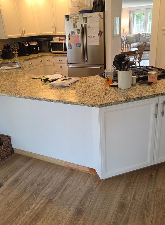 Before: A large peninsula-style kitchen countertop and island with dated design blocks walkway before renovation